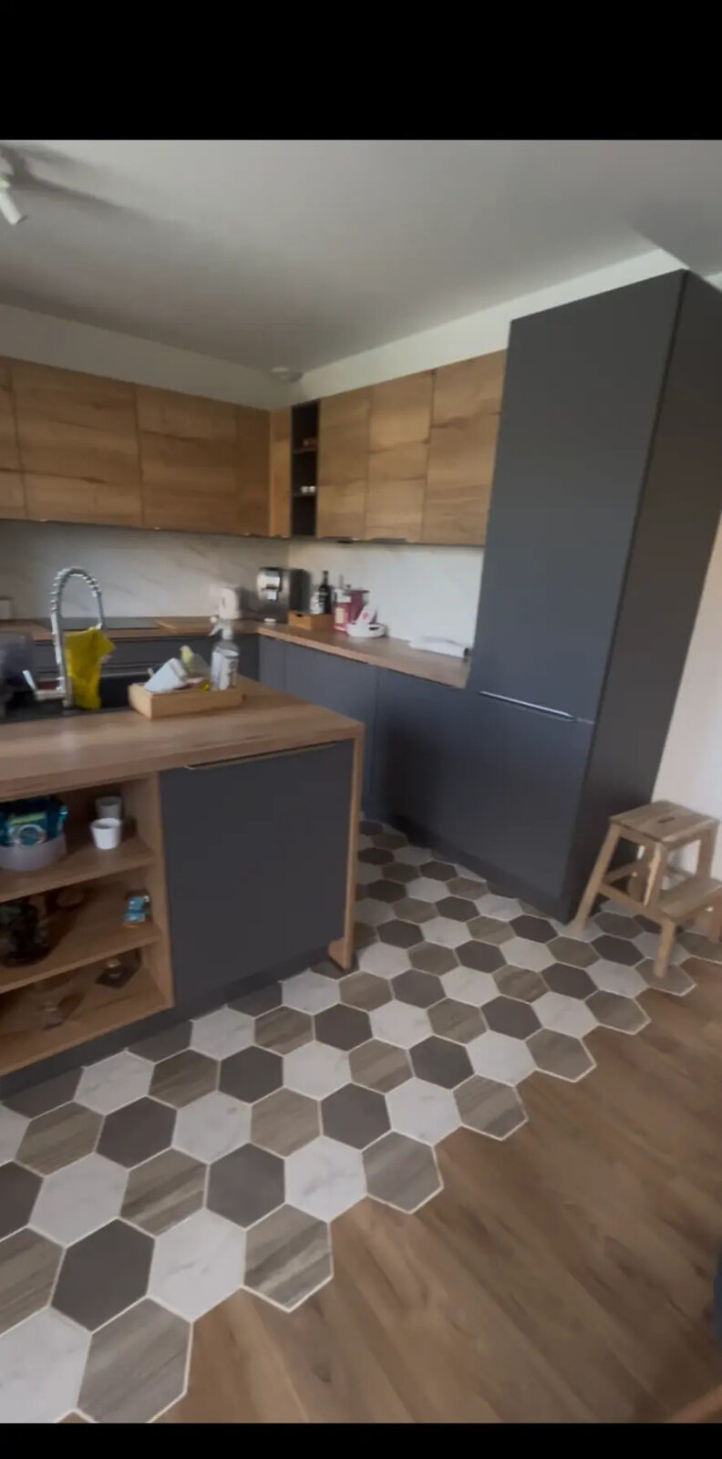 Cuisine moderne avec carrelage hexagonal, raccord parquet, îlot et plan de travail en bois