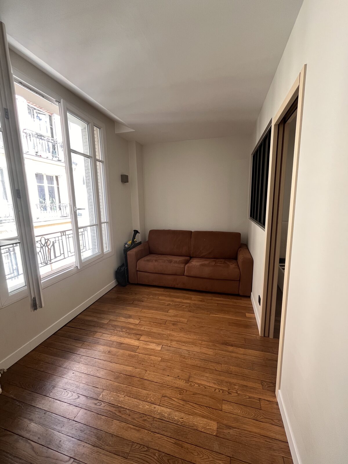 Séjour rénové avec murs et plafond repeints en blanc et parquet bois
